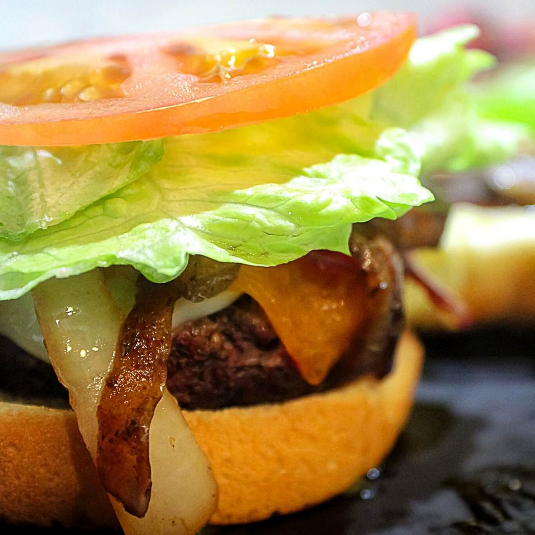 cowboy burger featuring bun, burger, cheddar and swiss cheeses, sauteed onions and mushrooms, lettuce, tomato, bbq sauce and mayo.